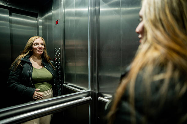 istock Pregnant woman looking at herself in the elevator mirror 2232356779