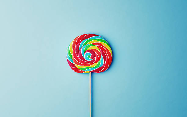 istock Multicolored Flavored Spiral Candy Lollipop on Blue Soft Background 2232357971