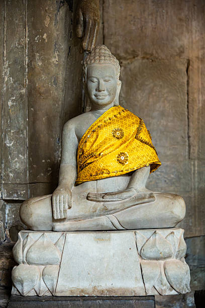 A serene Buddha statue dressed in an intricate golden fabric, located in Cambodia's renowned Angkor Wat. A peaceful and spiritual ambiance surrounds this ancient cultural landmark.