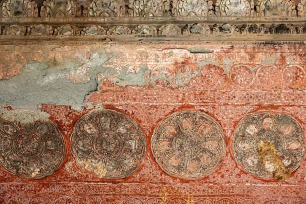A detailed view of a weathered and textured wall within the historic Angkor Wat Temple, Cambodia, showcasing intricate patterns and shades of earthy tones, emphasizing the artistry and historical significance of the structure.