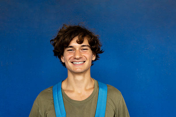 Portrait of a cheerful young male tourist smiling against a vibrant blue backdrop