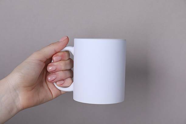 istock Woman holding blank white mug on grey background, closeup. Mockup for design 2232360588