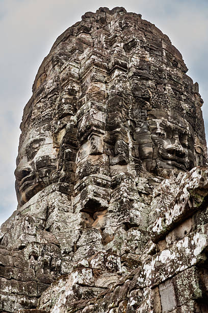 Historic sculpture of stone faces at Bayon Temple in Angkor Thom, Cambodia, showcasing detailed ancient Khmer architecture and craftsmanship, embodying a serene yet mystical atmosphere amidst a lush natural backdrop.