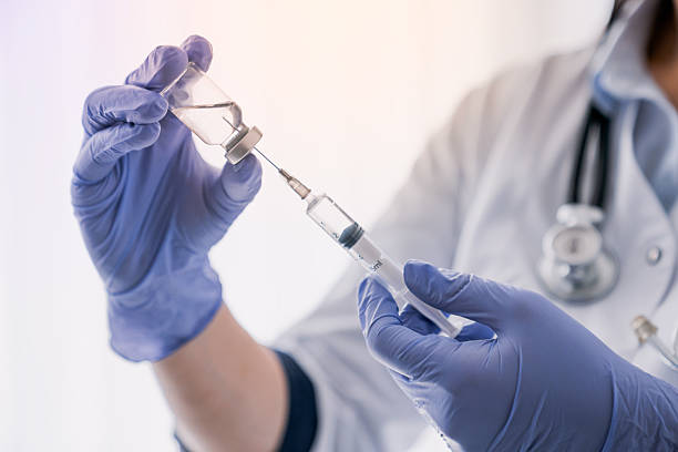 istock Medication nurse wearing protective gloves get a needle ready for an injection. Remedy medicine drug in ampule. Anesthesia, coronavirus vaccination. Hepatitis, flu vaccine 2232362366