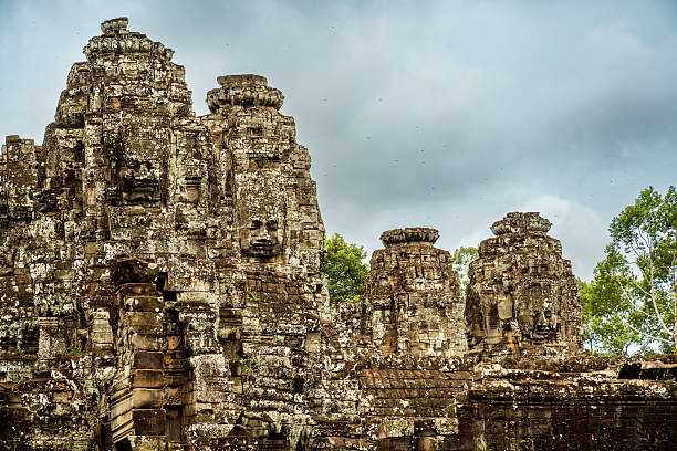 Historic sculpture of stone faces at Bayon Temple in Angkor Thom, Cambodia, showcasing detailed ancient Khmer architecture and craftsmanship, embodying a serene yet mystical atmosphere amidst a lush natural backdrop.