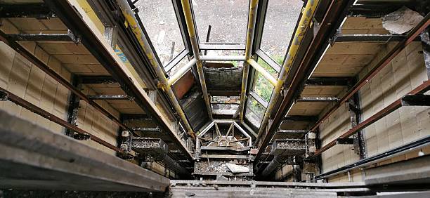 Collapsed elevator shaft, crashed and burned out. Fallen glass lift accident, fire damaged. Vandalised and arson, like scene from towering inferno. Vertigo looking down on burnt wreckage. Twisted metal staring into abyss suffering acrophobia, claustrophobia. High up tower vandalised, leaving rusty crumbling post apocalyptic empty remains.