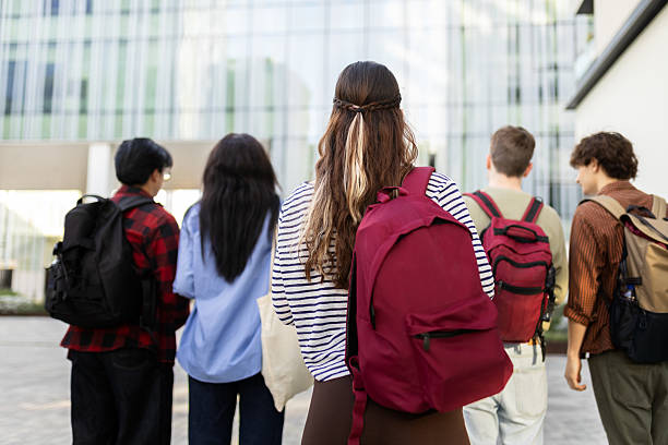 istock Students walking outside university building carrying backpacks 2232369811