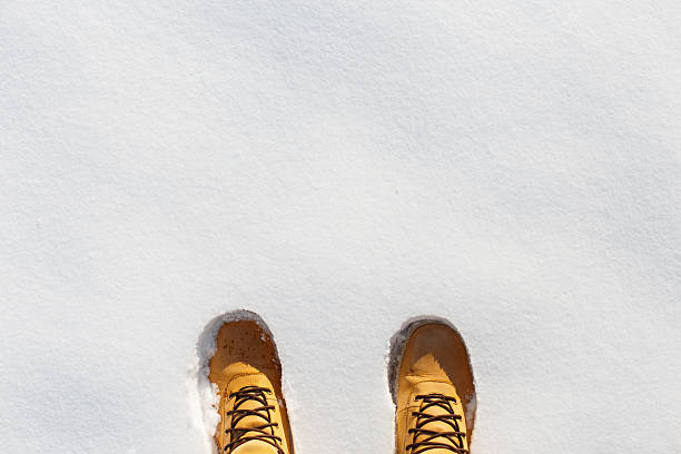 Human legs with leather yellow boots standing in the snow. Top view