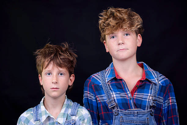 Brothers dressed in check shirts and bib overalls.