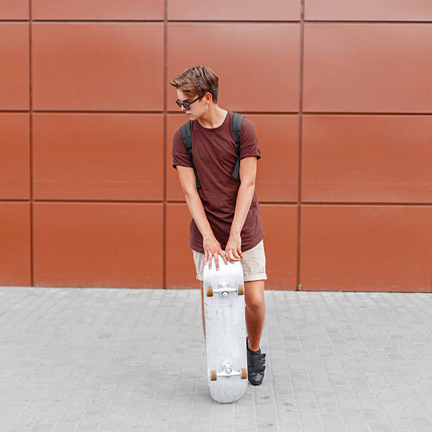 istock Handsome man posing with skateboard near the wall 2232371412
