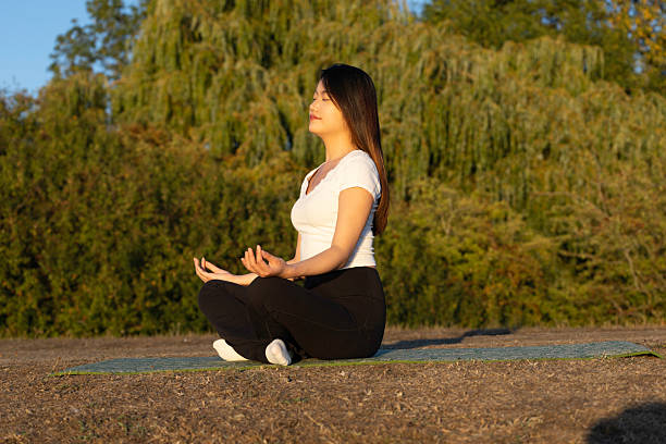 istock Young Woman is doing meditation at Sunset 2232373519