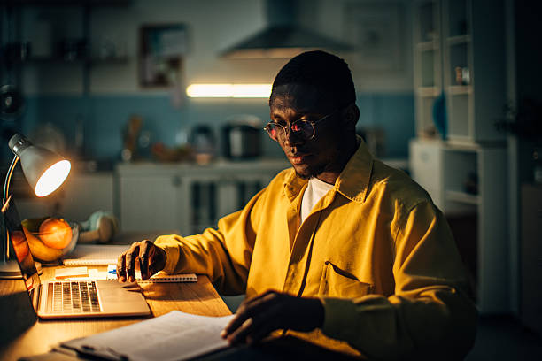 istock Young black man working diligently at home during the night in a cozy kitchen environment 2232373528