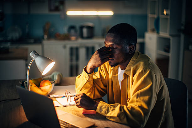 istock Young black man working late at home in a warm, cozy kitchen environment while feeling stressed 2232373773