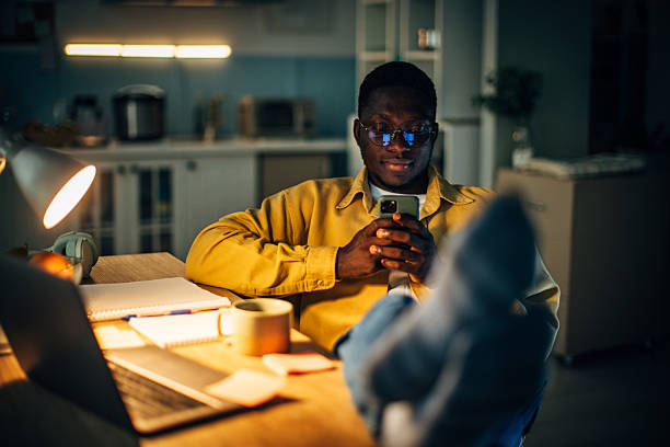 istock Young black man relaxes at home during the night while using his smartphone after a long day 2232375225