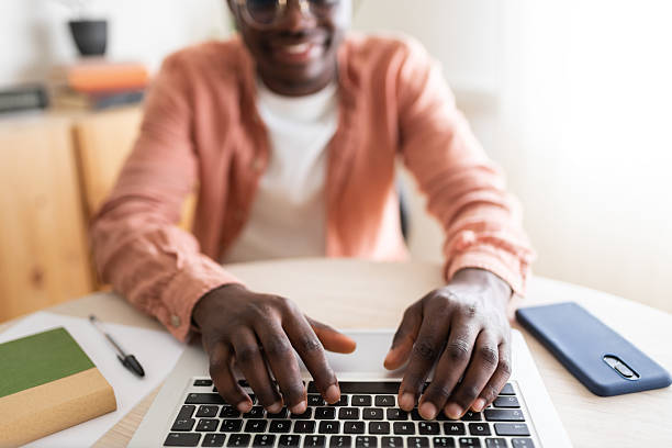 Young black man working from home typing on his laptop keyboard
