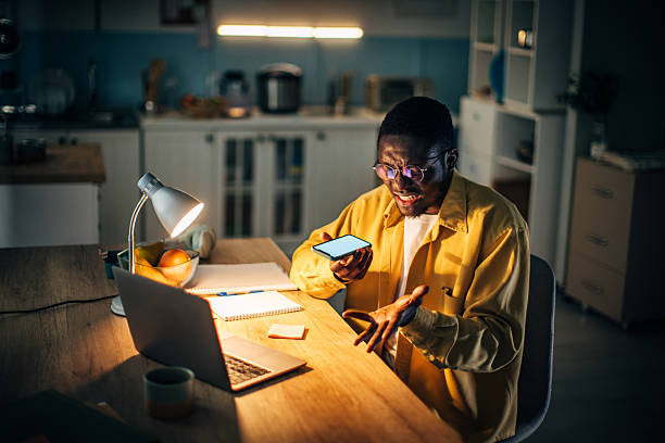 istock Young black man engaged in conversation while sitting at a desk in his home at night 2232375461