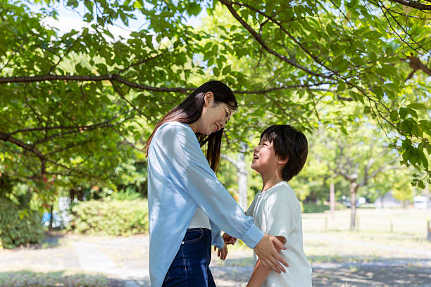 Mother and son talking under the trees in public park