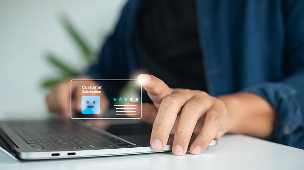 istock Hand using a laptop with a hologram customer satisfaction icon showing a neutral face and a three-star rating. Concept of average review, online feedback, consumer experience, and service evaluation. 2232376797