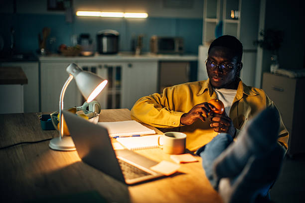 istock Young black man relaxing at home during the night while working on his laptop and enjoying a cup of tea 2232377662
