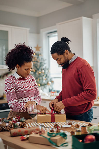 istock Smiling black couple wrapping Christmas gift box at home. 2232378014