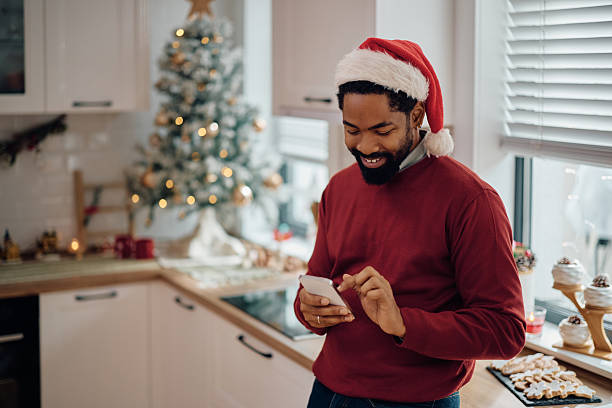 istock Happy black man using smart phone on Christmas day at home. 2232378959