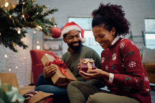 istock Happy black couple exchanging presents under a Christmas tree. 2232379018
