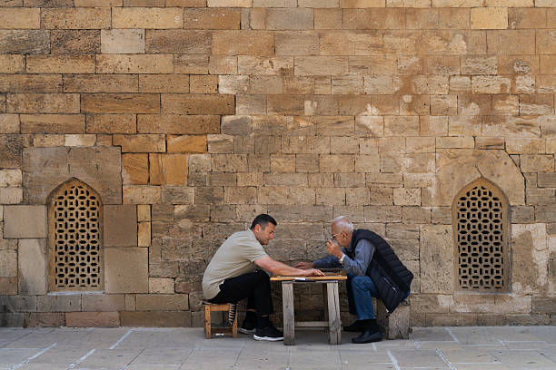 Scicli (Ragusa Province), Sicily: Three youths walking past three senior men sitting on a bench in Scicli, a UNESCO World Heritage town in Ragusa Province.