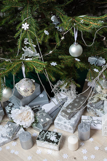istock Modern and chic steel-tone gift boxes arranged beneath a beautifully decorated Christmas tree, complemented by candlelight and festive accents for a serene holiday mood 2232379642