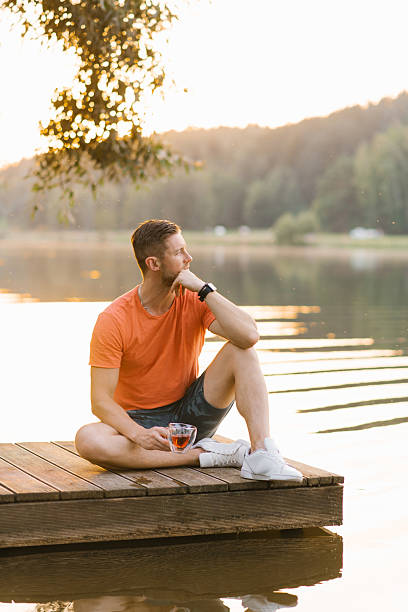 istock Relaxing Man Sitting On Wooden Pier 2232380817