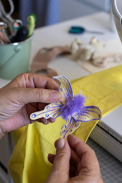 A small green handmade pin cushion wrapped with a bright yellow ribbon, adorned with colorful pins. Ideal for sewing, quilting, and crafting enthusiasts