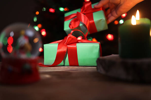 istock Placing Wrapped Presents Near a Lighted Candle for Christmas Celebration 2232381571