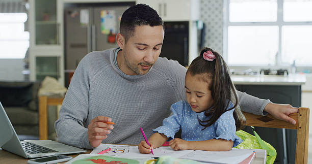 istock Creative, girl and homework with dad, home or coloring for preschool project, remote work or growth. Child, learning and development with education, assistance and man with laptop for freelance task 2232381606