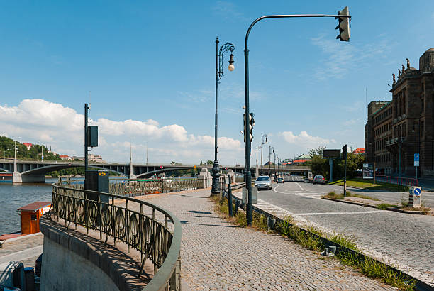 Prague, Czech - August 22, 2013 - Scenic urban riverside with bridge on a clear day.