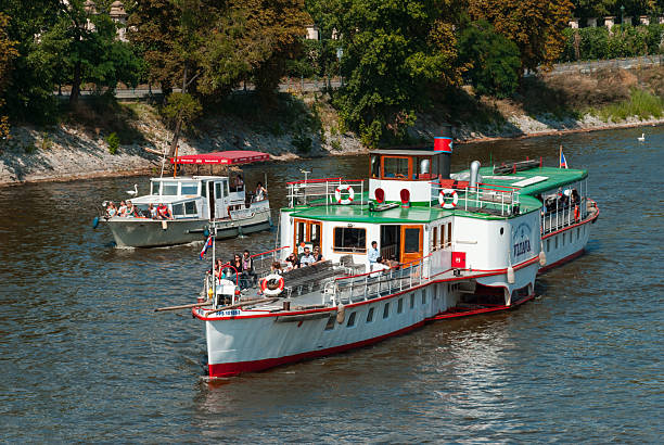 Prague, Czech - August 22, 2013 - Sightseeing boats on river with tourists on sunny day.