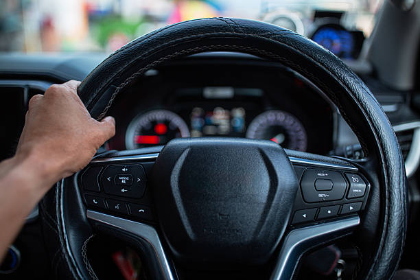 istock Car steering wheel and control buttons with human hands close up,Woman's hand presses the button on the steering wheel of the car close-up. Multi function buttons on steering wheel in car. 2232389900