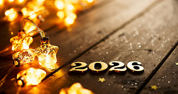 istock Golden 2026 Numbers with Glowing Star Lights on Rustic Wooden Surface 2232392797