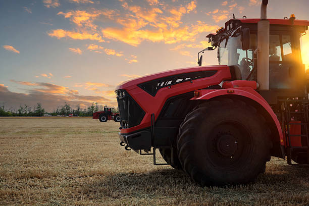 istock Several large modern red tractors stand in a field against a beautiful sunset sky. 2232393996