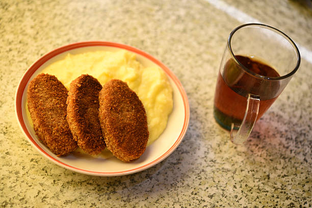 Three fried meat patties and mashed potatoes on a plate. Delicious breakfast with meat and tea.