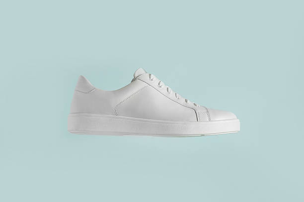 istock Woman hand holding stylish white sneaker on light blue background. 2232396442