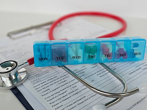 istock Weekly medication organizer sits on a medical form with a stethoscope 2232398177