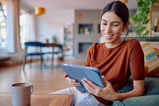 istock Young Woman Relaxing on Sofa Using Digital Tablet at Home 2232398653