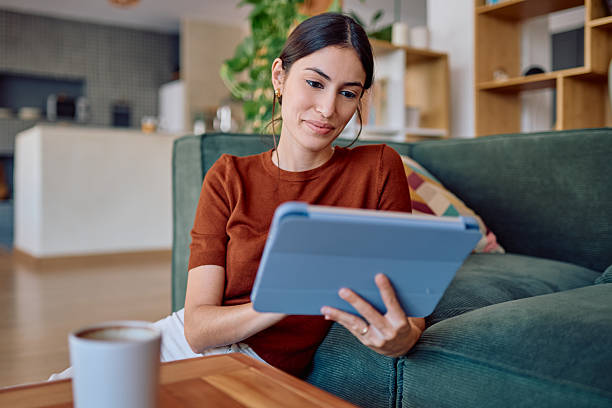 istock Young Woman Relaxing on Sofa Using Digital Tablet at Home 2232398654