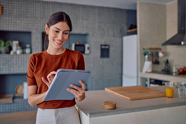 istock Young Woman Using Digital Tablet in Modern Kitchen 2232398784