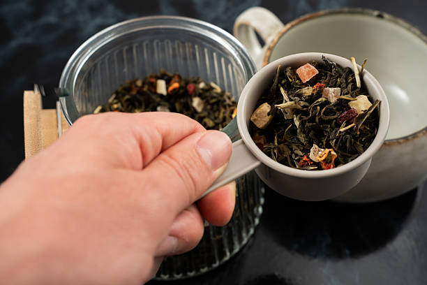 istock Hand scooping loose leaf tea into a cup in a cozy kitchen setting during the afternoon 2232399109