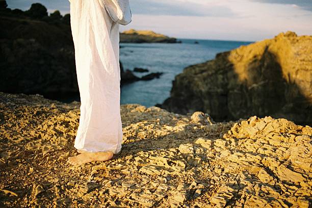 istock Barefoot person standing on coastal rock at sunset 2232401084