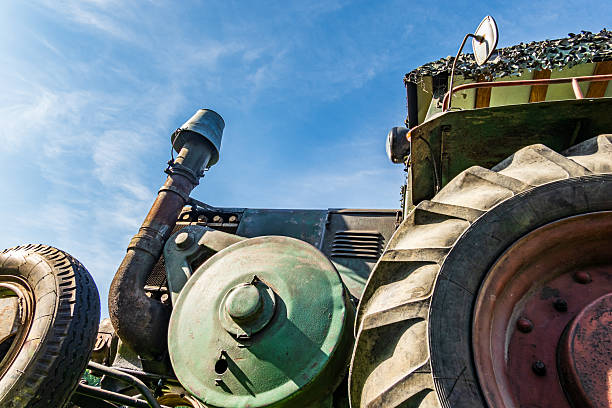A vintage tractor sits under a bright blue sky, showcasing its rustic charm and details as sunlight reflects off its metallic surfaces.