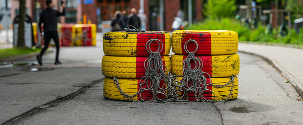 Stacked painted tires with chains on street.