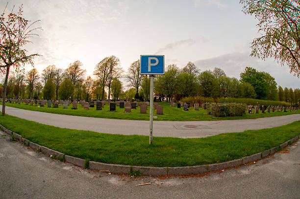 Blue parking sign facing twilight cemetery.