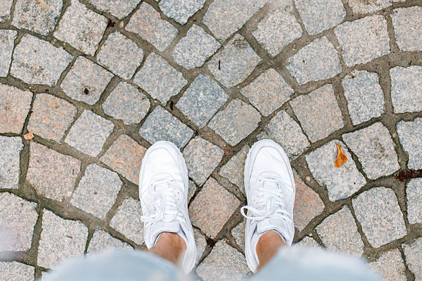 Young man traveling on summer vacation. White sneakers on tile.