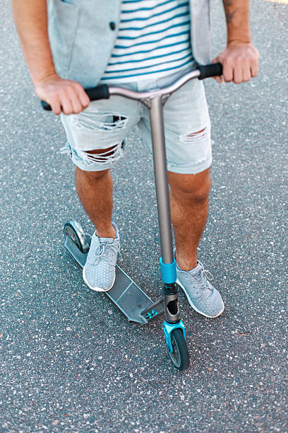 istock Kick scooter on the asphalt. Stylish man riding a scooter. 2232409357